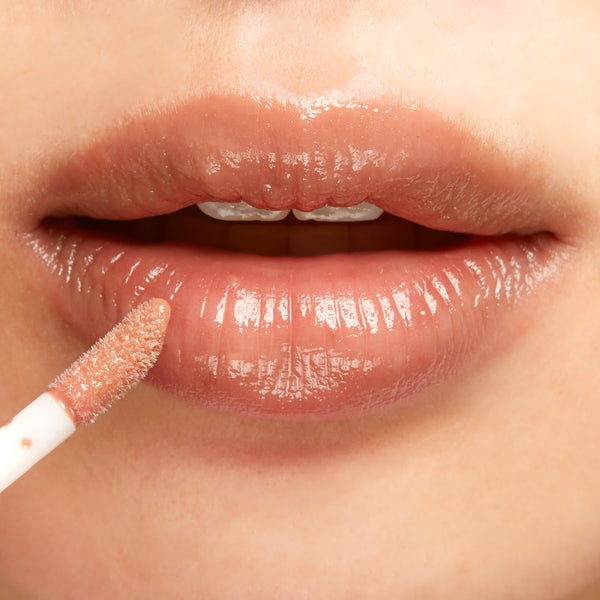 Close-up of a person applying lip gloss with a brush.