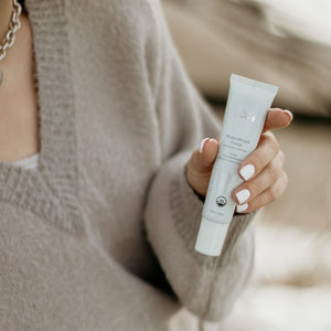 Person holding a skincare product with a neutral background