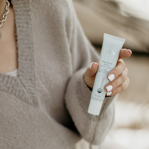 Person holding a skincare product with a neutral background