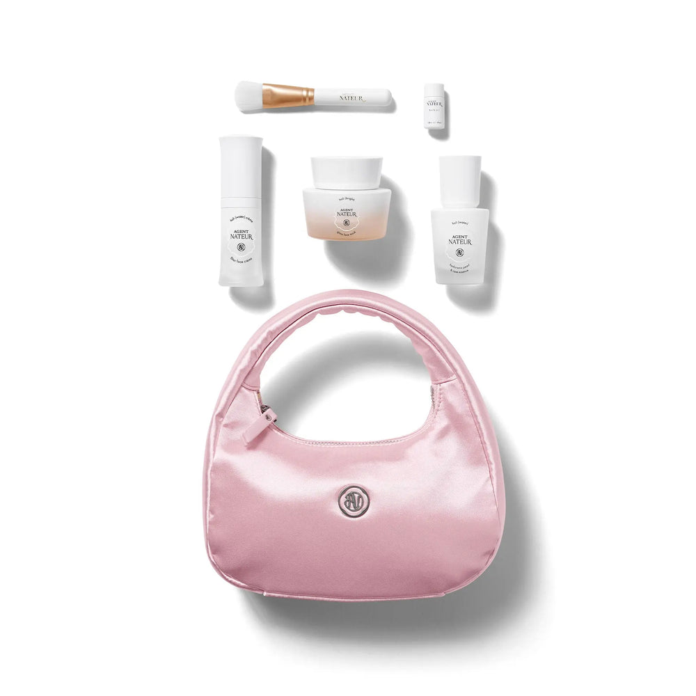 Pink handbag with skincare products on a white background