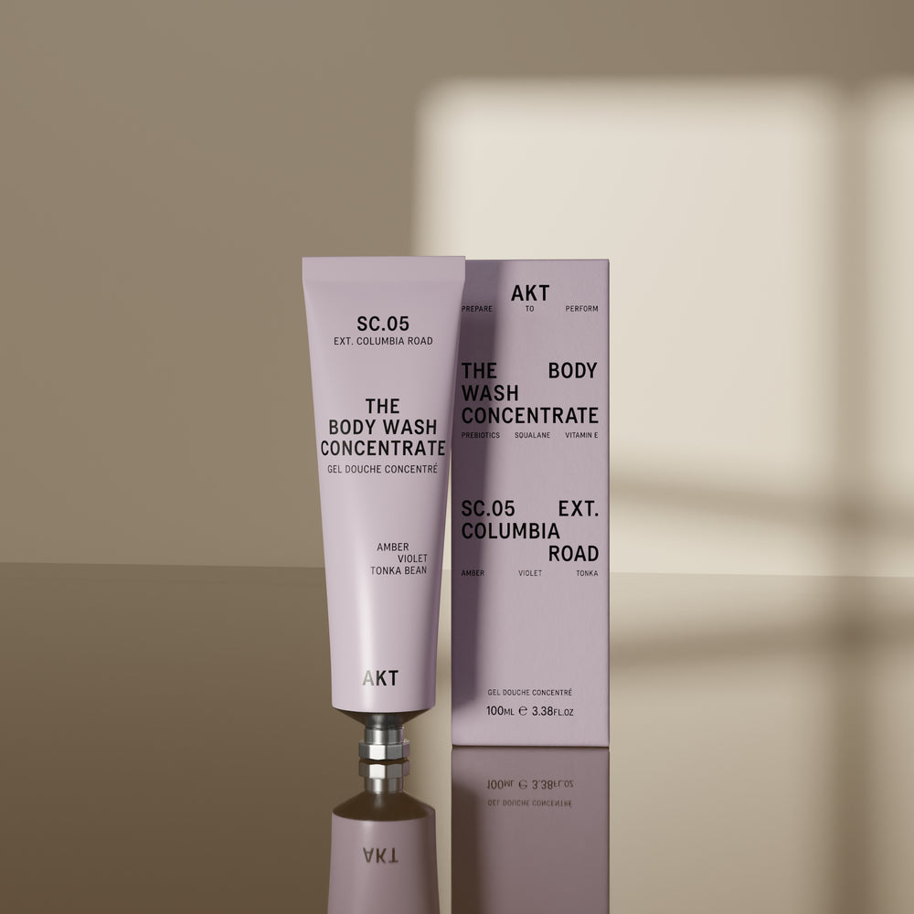 A lavender tube of AKT London The Body Wash Concentrate, SC.05, on a light off-white background with a soft shadow.