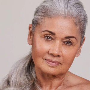 Close-up of a woman with gray hair against a plain background wearing ALEPH Mixing Face Balm