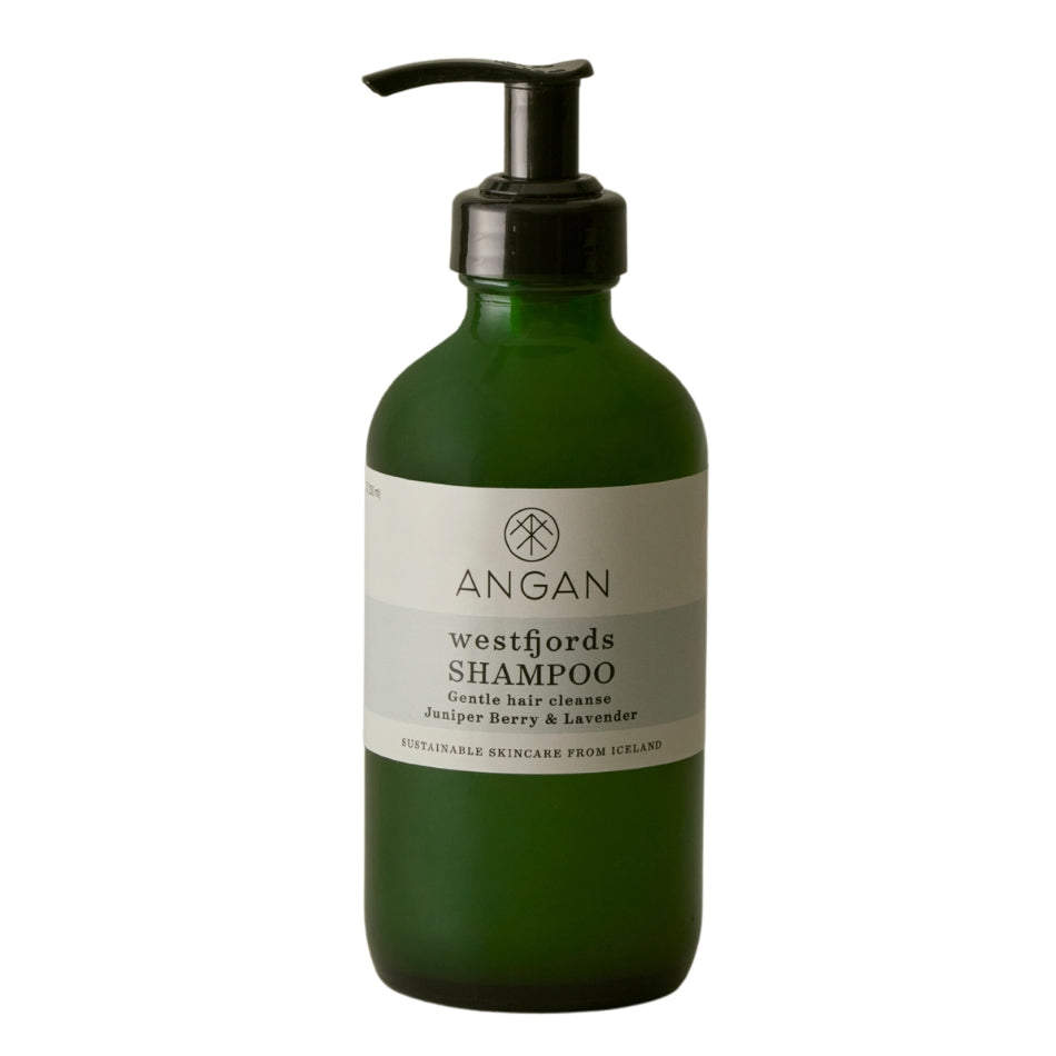 A dark green glass bottle of Angan Westfjords Shampoo with a black pump dispenser and a white label, set against a plain white background.