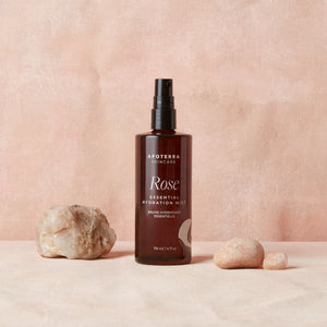 Brown bottle of Apoterra Rose Essential Hydration Mist on a beige background with stones.