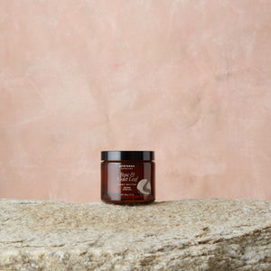 Jar of body butter on a stone surface with a pink textured background. Apoterra Rose & Violet Leaf Body Butter