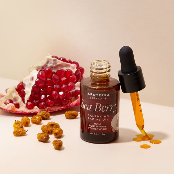 Apoterra Sea Berry Balancing Facial Oil with dropper and pomegranate seeds on a beige background