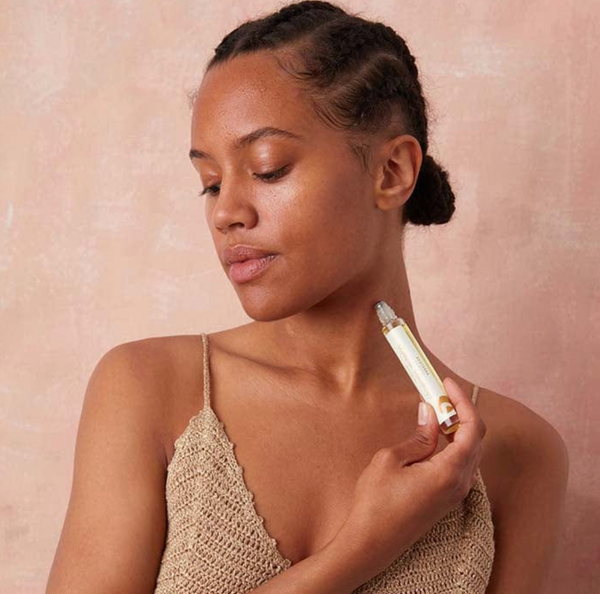 Woman applying APOTERRA Tulsi & Lavender Aromatherapy Oil with a pink background