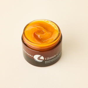 Jar of Vitamin C balm with a visible brand logo on a beige background