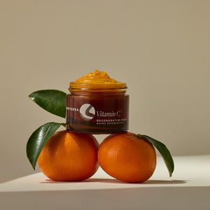 Jar of vitamin C balm with oranges and leaves on a beige background