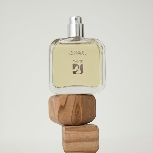 Rock Rose perfume bottle from Ayond with wooden blocks on a light gray background