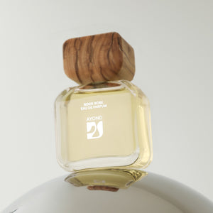 Perfume bottle with wooden cap on a reflective surface