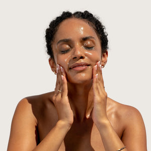 Woman applying BLOOMEFFECTS Royal Tulip Cleansing Jelly to her face against a plain background