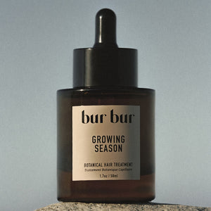 Brown glass bottle with dropper labeled 'bur bur' on a gray background