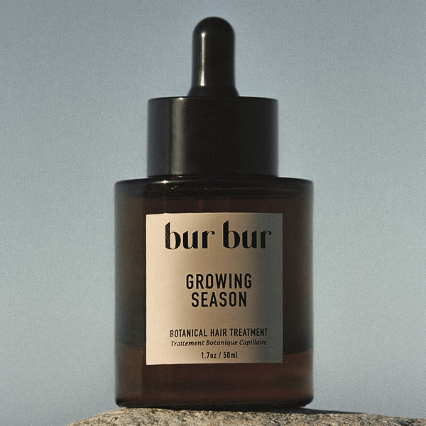 Brown glass bottle with dropper labeled 'bur bur' on a gray background