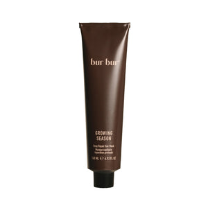 A brown colored tube with black cap of bur Bur Growing Season hair mask on white background