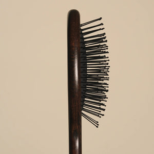 Wooden hairbrush with black bristles on a beige background