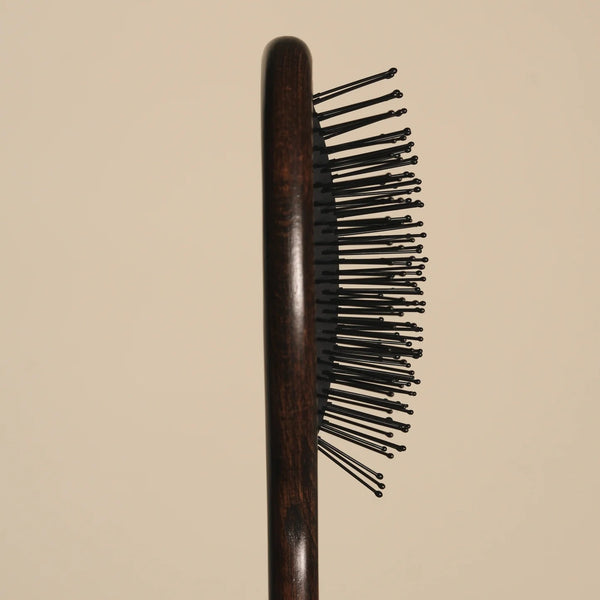Wooden hairbrush with black bristles on a beige background