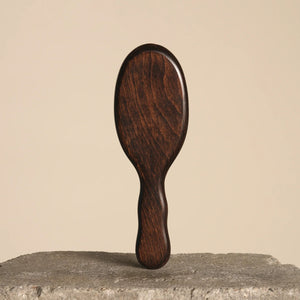 Wooden hairbrush on a textured surface with a beige background