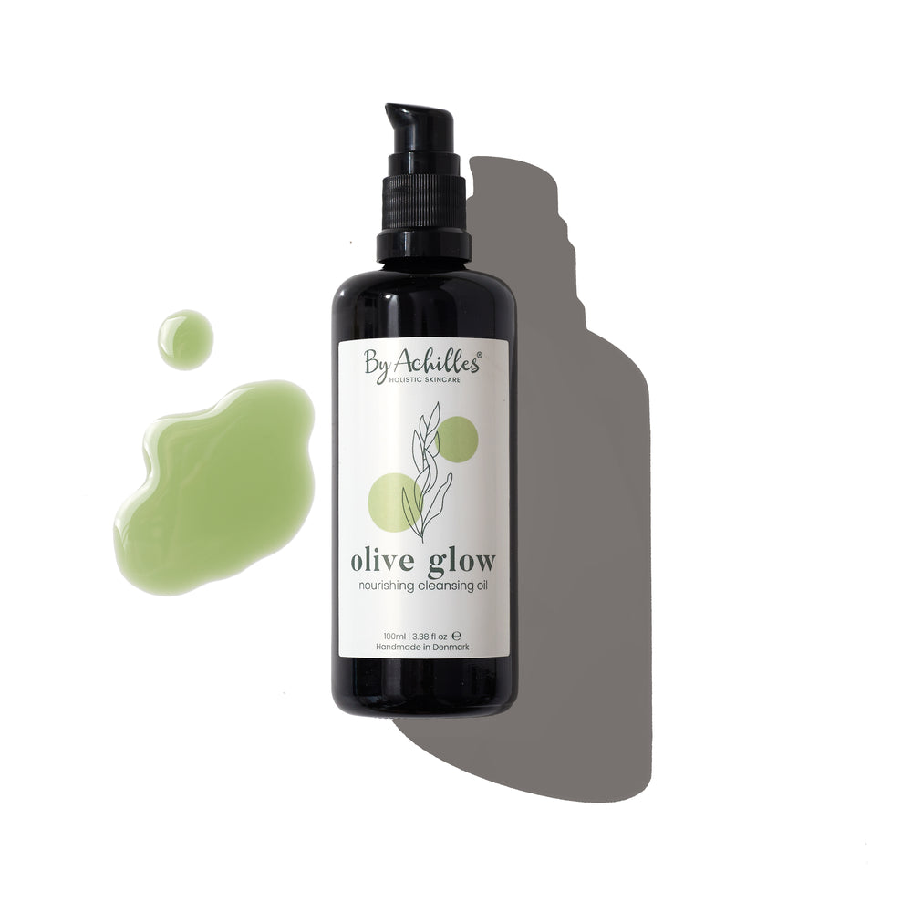 By Achilles Olive Glow™ Cleansing Oil in a glass bottle, designed for gentle cleansing and nourishment, featuring golden jojoba, olive oil, and blue tansy.