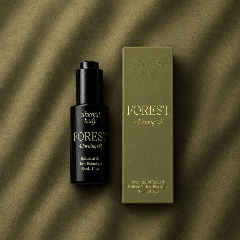 A black bottle of Forest Adorning Oil by Ethereal Body with gold lettering, shown against a solid white background.