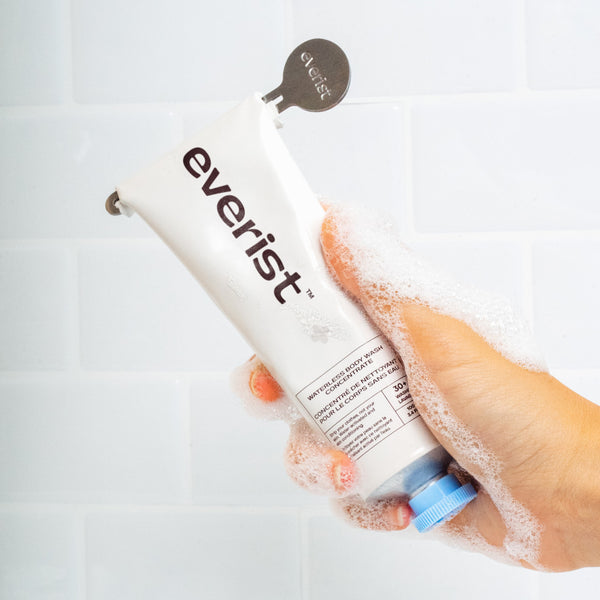 Hand holding a bottle of Everist The Body Wash Concentrate  with a white background