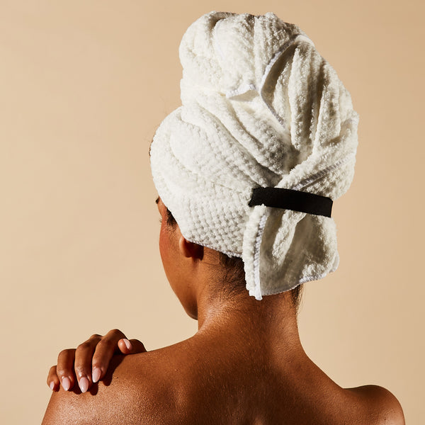 Person with a white towel wrapped around their head on a beige background