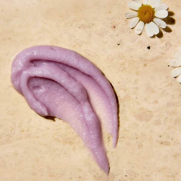 A texture shot of FREE + TRUE Moonlight Milk PM Balm Cleanser in purple color on beige background