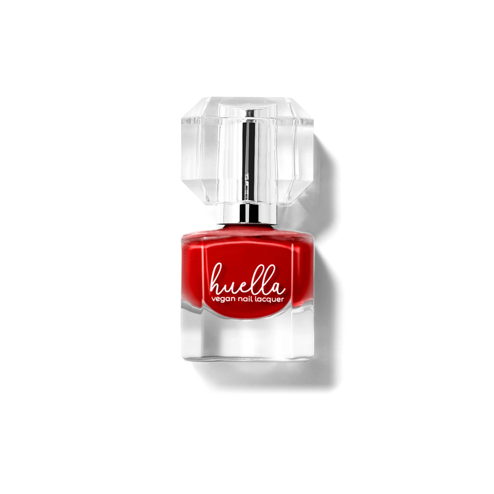 Huella Curtain Call nail lacquer in a bold crimson red shade, featuring a 15-free, vegan, and chip-resistant formula.