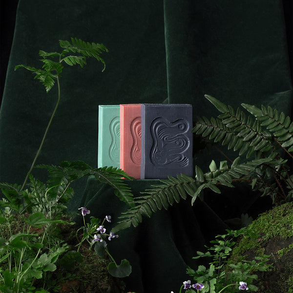 Three soap bars in green, red, and light black color on a dark background with foliage. INBLUEM Soul Soap Finger Lime & Eucalyptus