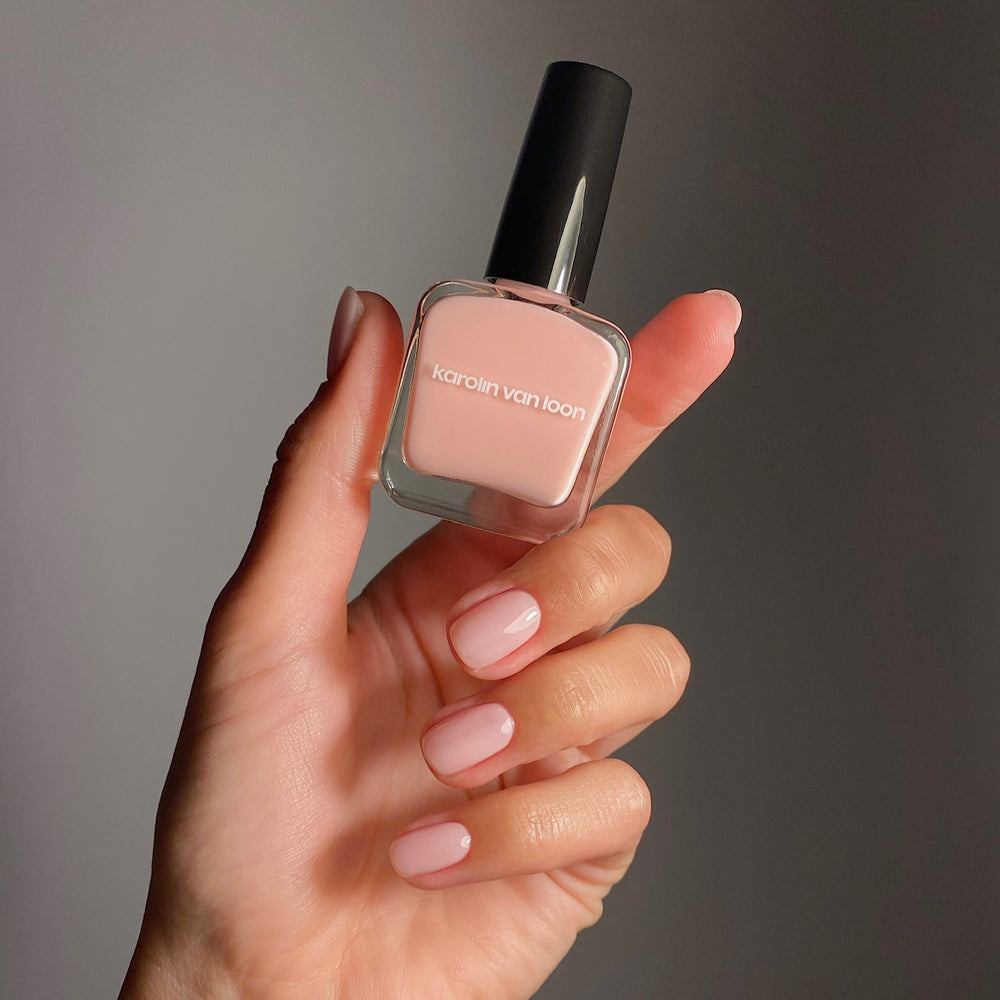 A bottle of Karolin Van Loon nail polish in shade 50 Rosé Doux, featuring a soft mademoiselle pink color perfect for all seasons, offering a delicate ballerina look in winter and a playful cotton candy hue for summer.