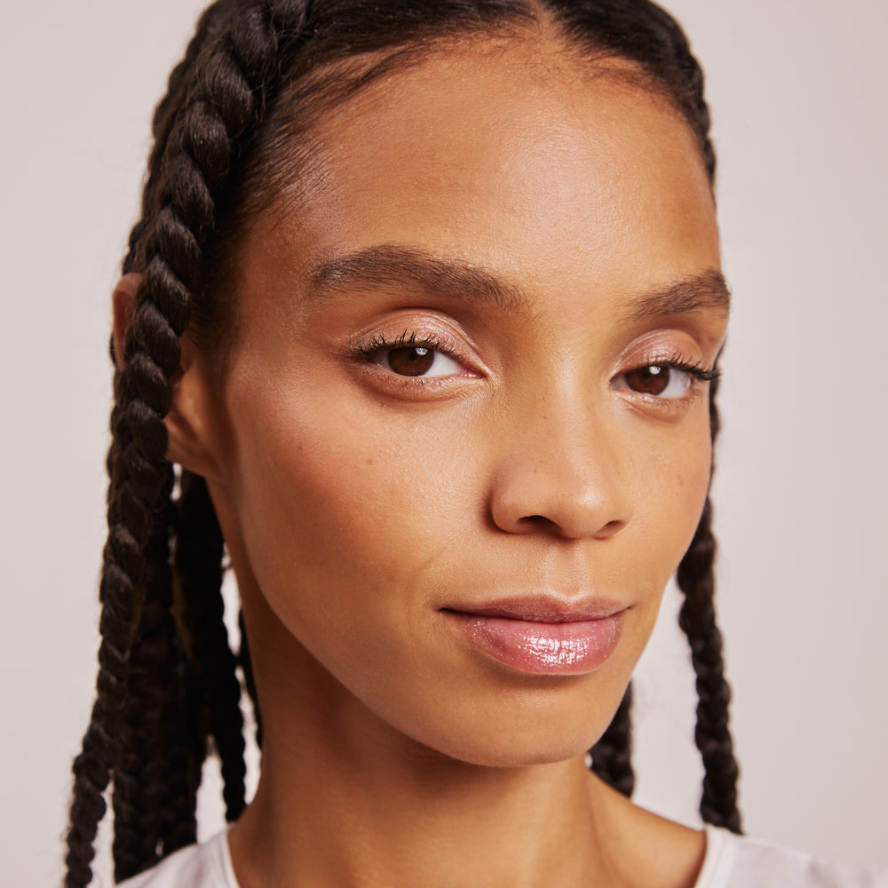 A tube of Karolin Van Loon lip gloss in Angel, featuring a transparent formula with a twinkle inspired by crushed crystals. This gloss offers a tingly, minty feel for irresistibly voluminous lips and delivers radiant shine with a subtle tint.