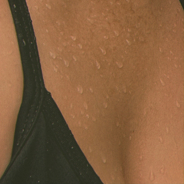 Close-up of a person wearing a black bralette on beige skin.
