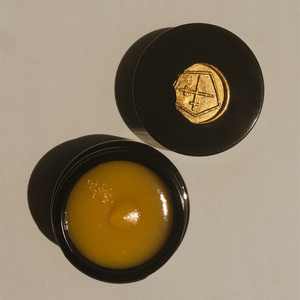 Black container with yellow soft balm and gold emblem on a beige background. LEPAAR Luminous Beauty Balm / Ultra Restorative Moisture Lock
