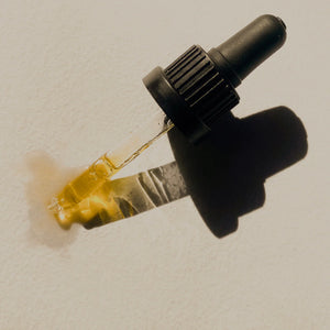 Dropper with yellow oil on a textured beige background. LEPAAR Yuzu Vitamin C Serum Complexion Saving Antioxidant Concentrate
