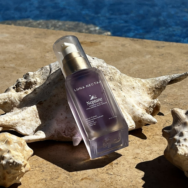 LUNA NECTAR Neptune Blur & Hydrate Hyaluronic Acid Serum skincare bottle on seashells with a beach background