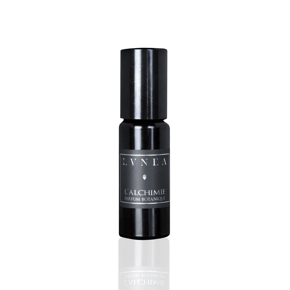 LVNEA L'alchimie Parfum Botanique in a 10ml black amethyst glass bottle with a glass roller ball, encased in a matte black tube. The fragrance features notes of blood orange, amber, and rose, creating a rich, warm, and floral scent profile.