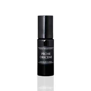 LVNEA Pêche Obscène perfume in a 10ml amethyst glass bottle with a roller ball, showcasing a blend of peach, jasmine, patchouli, and vetiver. Encased in a matte black tube, highlighting its rich, fruity, and earthy aroma.