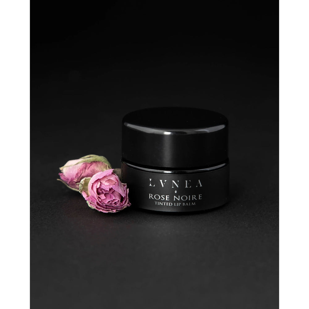 Luxurious Tinted Lip Balm: A rich, nourishing lip balm with a dark dusty rose tint, featuring botanical oils, butters, and natural rose wax. Offers a light floral fragrance and sweet taste, perfect for enhancing lips or as a dewy cheek stain.