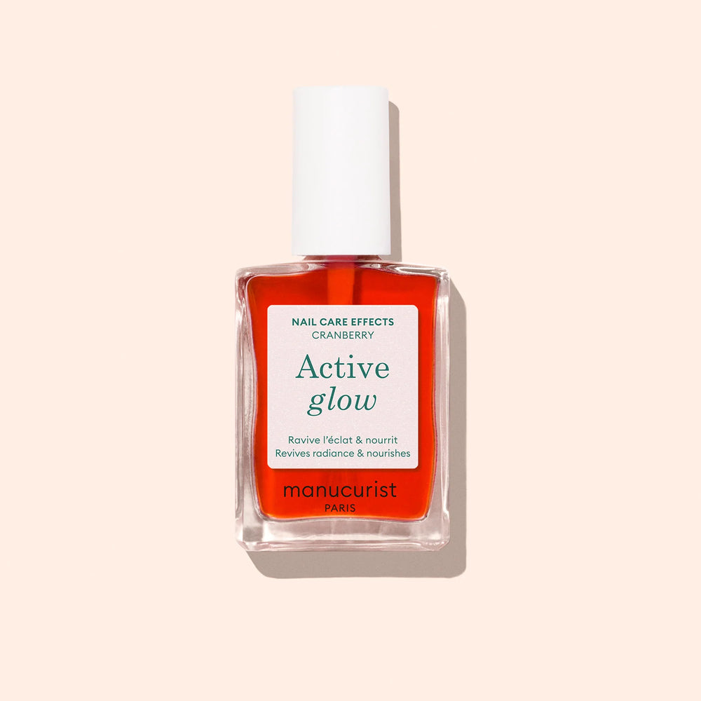 Bottle of MANUCURIST Active Glow™ Cranberry coral nail polish with a glossy, translucent finish.