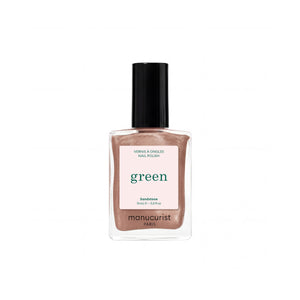 A bottle of Manucurist nail polish in the shade Sandstone, featuring a clear glass bottle filled with a shimmering sandstone-brown polish, a light pink label with green text, and a black cap, set against a plain white background.