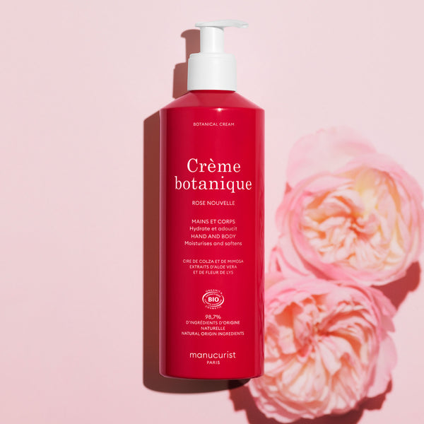 Red bottle of Crème botanique with pink flowers on a pink background 500ml