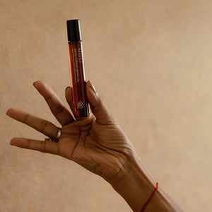 Hand holding MAULI RITUALS Grow Strong Brow Oil against a beige background