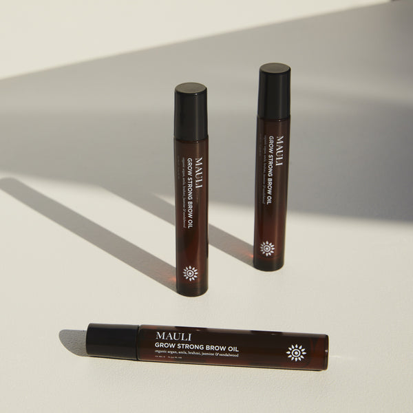 Three bottles of MAULI Grow Strong Brow Oil on a light background