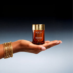 Hand holding a Mauli Rituals Rose & Saffron Radiance Mask product against a gradient background