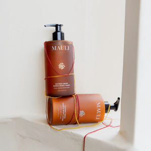 Two bottles of Mauli Rituals hand and body wash and lotion on a white surface with a light background