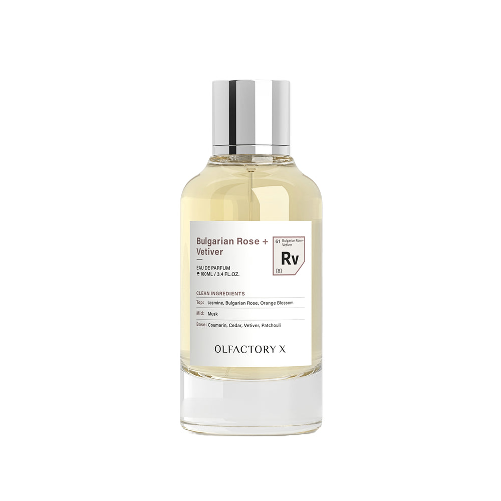 A clear glass bottle of Olfactory X Bulgarian Rose + Velliver Eau de Parfum with a silver cap, containing a pale yellow liquid, set against a plain white background.