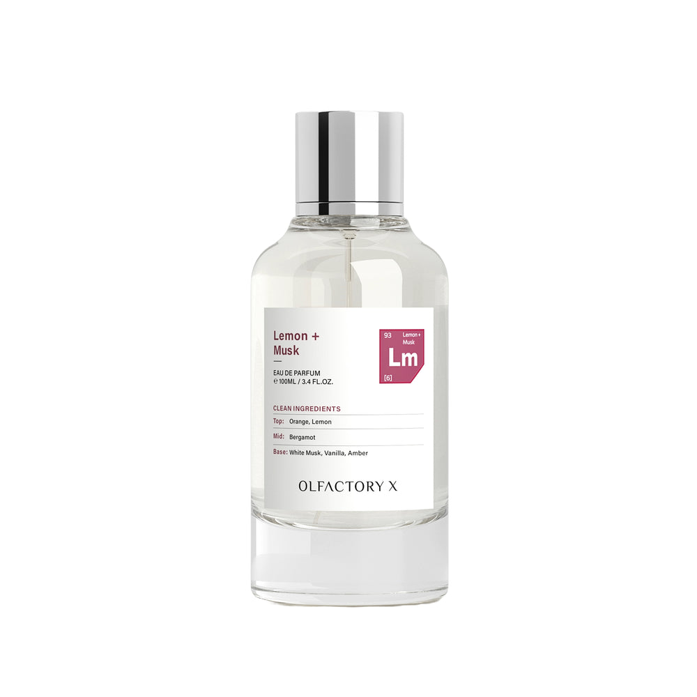 A clear glass bottle of Olfactory X Lemon + Musk Eau de Parfum with a reflective silver cap and a white label, set against a plain white background.