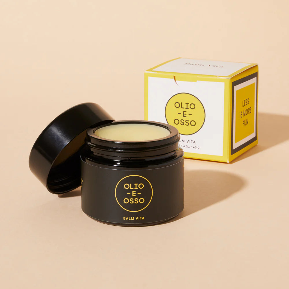 Black jar of Olio E Osso balm with open lid and packaging on a white background