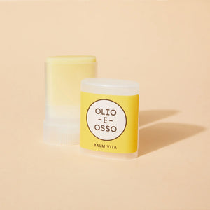 Yellow tube of Olio E Osso Balm Vita on a beige background