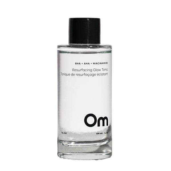 Clear bottle of Om skincare tonic with black cap on a white background